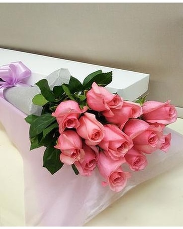 Disposition de douze fleurs roses dans une boîte