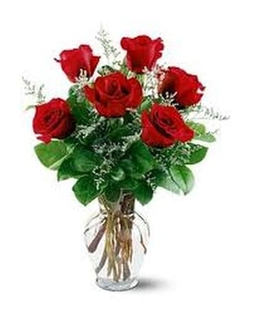 Six roses rouges dans une composition florale en vase