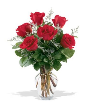 Six roses rouges dans une composition florale en vase