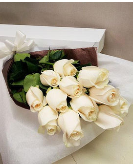 Douze roses blanches disposées dans une boîte fleurie